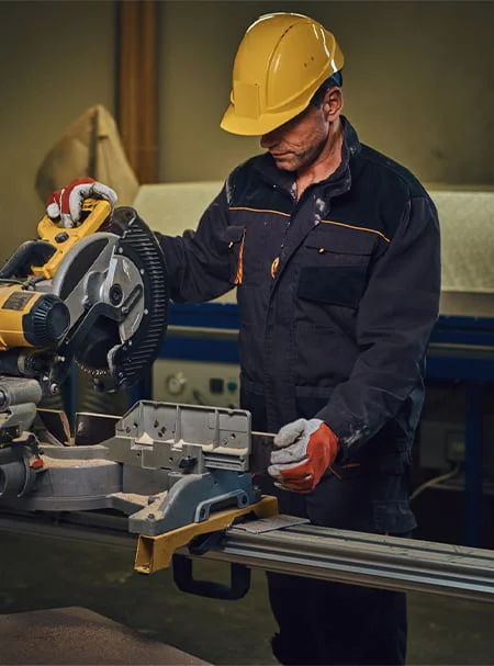 FLYZONE Engineering worker operating an industrial circular saw for precise metal cutting, demonstrating safety and accuracy in fabrication processes.